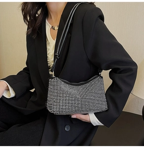 Gros plan d'un sac hobo noir orné de strass brillants porté par un mannequin élégant