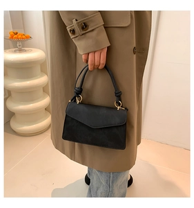 Detail of black matte handbag with gold metal ring and decorative knot strap detail