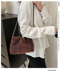 Detail of multi-color plaid bucket bag featuring a drawstring closure and silver chain strap