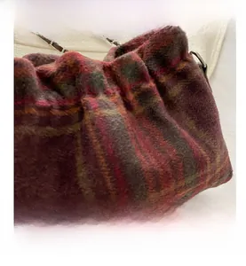 Detail of wool bucket bag showing red and green tartan fabric and chain strap