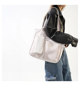 Vista detallada de un bolso tote de nailon rosa claro con una bolsa pequeña a juego y bolsillo frontal