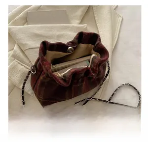 Detail view of red plaid wool bag interior showing magnetic buckle and chain strap