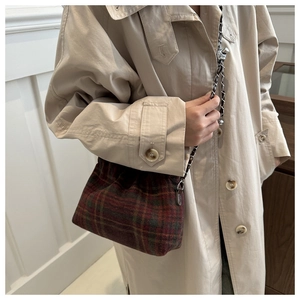Detail of red and green plaid wool crossbody bag with a silver chain and leather strap