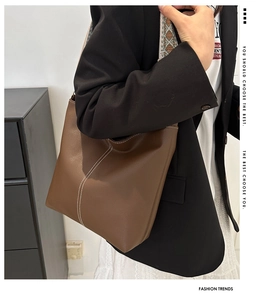 Detail of dark brown pebble leather tote bag with contrast stitching and ethnic strap