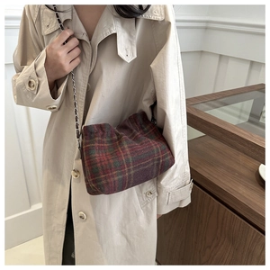 Fashionable wool plaid bucket bag with gold chain strap worn over a khaki trench coat