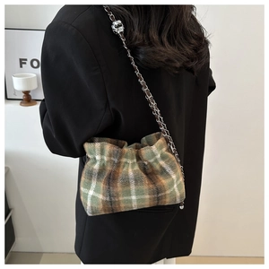 Detail of plaid wool bucket bag with chain strap styled on a black blazer jacket