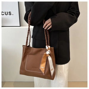Primo piano della borsa tote marrone con manici intrecciati e dettaglio foulard in seta