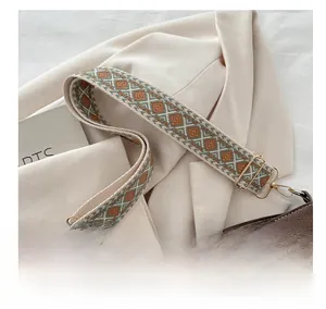 Close-up of geometric jacquard shoulder strap with golden metal hardware on bucket bag