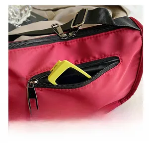 Macro detail of the anti-theft side zipper pocket on a durable red nylon shoulder bag
