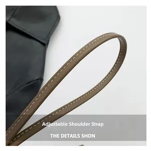Détail d'une bandoulière réglable en cuir marron avec surpiqûres blanches sur sac noir