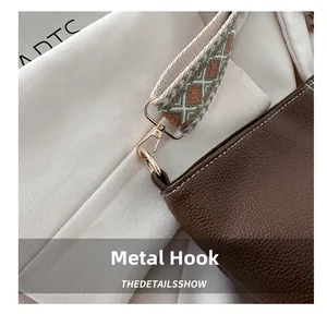 Detail of light gold alloy hook on brown litchi leather bag with jacquard strap
