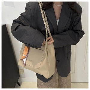 Détail du sac cabas en cuir beige avec poignée tressée et foulard en soie décoratif