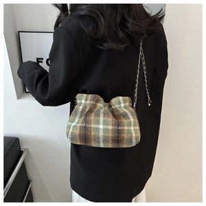 Detail of green plaid wool bucket bag with textured pleats and woven metal chain strap