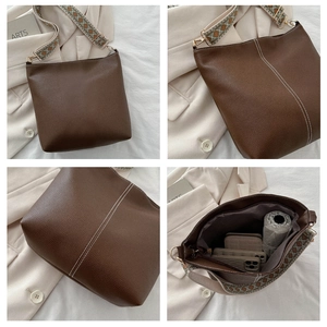 Close-up of brown litchi leather bucket bag with contrast stitching and wide woven strap