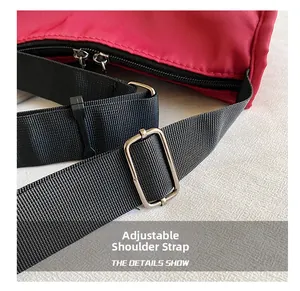 Detail of red nylon bag featuring adjustable black woven strap and silver metal buckle