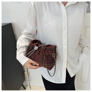 Detail of red-brown checkered bucket bag featuring wool texture and silver metal chain