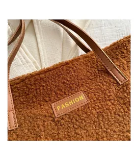 Détail d'un sac cabas marron en peluche avec étiquette en cuir FASHION et poignée