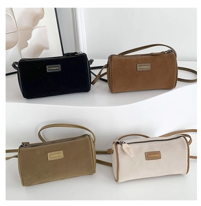 Dettaglio di quattro mini borse a cilindro in camoscio opaco nero, marrone, kaki e crema