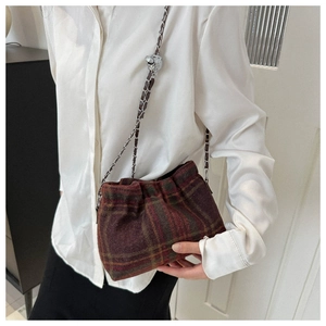 Detail of wool bucket bag featuring classic plaid texture and silver chain strap