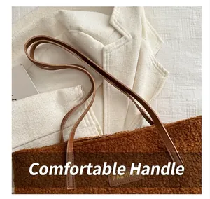 Détail d'un sac cabas en peluche marron avec anses en cuir et logo sur un blazer blanc