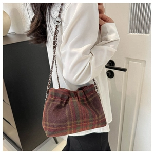 Detail of wool bucket bag featuring classic red and green plaid pattern and chain strap
