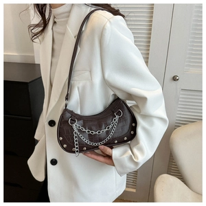 Detail view of dark brown faux crocodile leather bag with silver chain and rivets