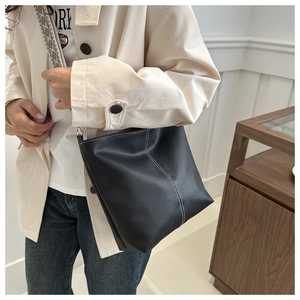 Detail of black lychee grain bucket bag with white stitching and patterned wide strap