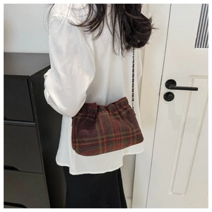 Close-up of vintage plaid wool bucket bag with drawstring top and metal chain strap