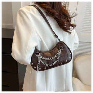 Detail of brown crocodile embossed underarm bag with silver chain and metal studs