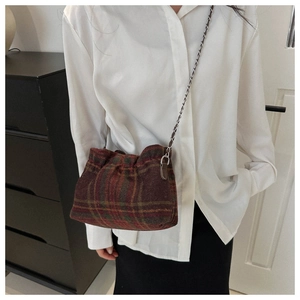 Close-up of red and green plaid woolen bucket bag with elegant silver chain strap