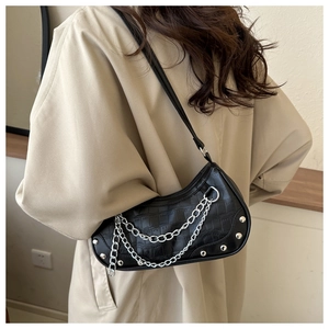 Close-up of black crocodile embossed shoulder bag with silver chain and rivet details