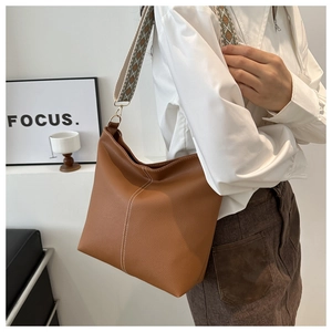 Detail of caramel brown lychee leather bag with jacquard strap and white stitching