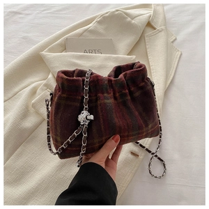 Detail of red plaid fabric texture and silver knot chain on a stylish bucket bag