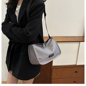 Detail of grey nylon crossbody bag featuring double silver zippers and adjustable black strap