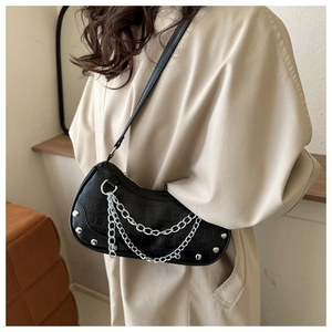 Detail view of black crocodile pattern underarm bag with silver chain and rivet accents