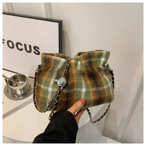 Detail of wool bucket bag with green plaid pattern, chain strap, and silver metal ball