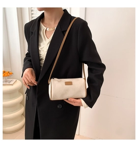 Détail d'un sac bandoulière cylindrique en daim avec bordure marron et bandoulière