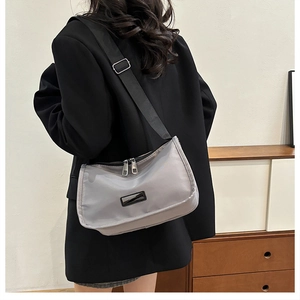 Detailed back view of a woman wearing a lightweight grey nylon crescent crossbody bag