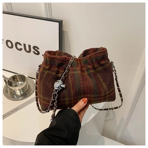 Detail of wool bucket bag with vintage red green plaid and metal chain strap held by hand