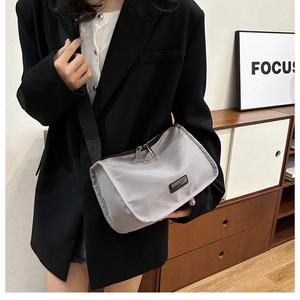 Nylon crossbody pillow bag with dual zippers and wide shoulder strap shown on model