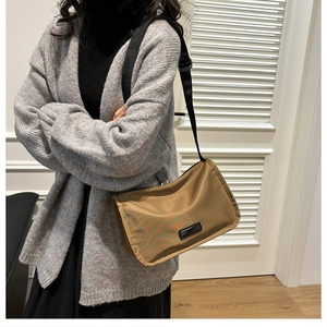 Model wearing a khaki nylon crossbody pillow bag with adjustable wide shoulder strap