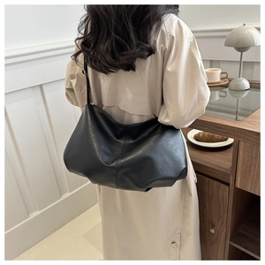 Minimalist black soft PU leather tote bag with pleated design worn by a model in a city setting