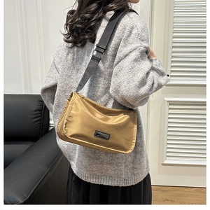 Light brown nylon crossbody bag worn by model with adjustable wide black shoulder strap