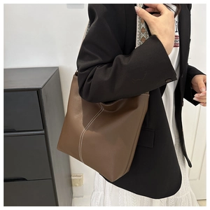 Brown bucket bag with white V-stitching and ethnic style geometric woven strap detail