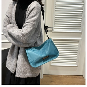 Blue nylon pillow bag with wide strap shown on model for a casual and stylish look