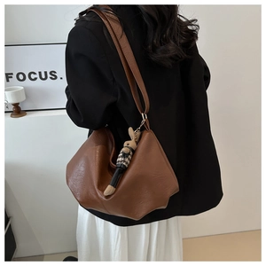 Detail der braunen Hobo-Tasche mit süßem Kaninchen-Anhänger und breitem Schultergurt