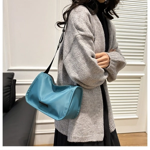 Detail of blue nylon crossbody bag with adjustable wide shoulder strap and logo patch