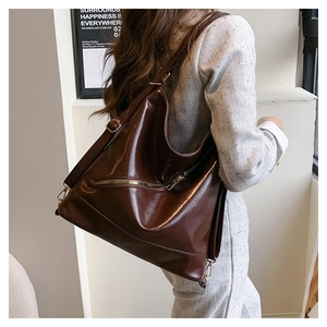 Detail of dark brown leather tote bag with metal zipper and adjustable long shoulder strap
