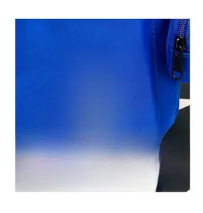 Detail of blue nylon school bag featuring a colorful WAAII letter patch and black zipper