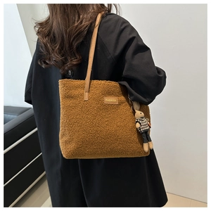 Dettaglio borsa tote in pile color caramello con manici in pelle e ciondolo a coniglio